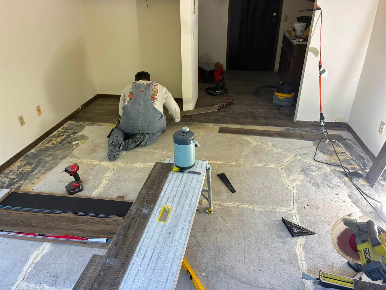 A 10-4 Handyman worker installing flooring, with tools laid out on a clean, protected work area.