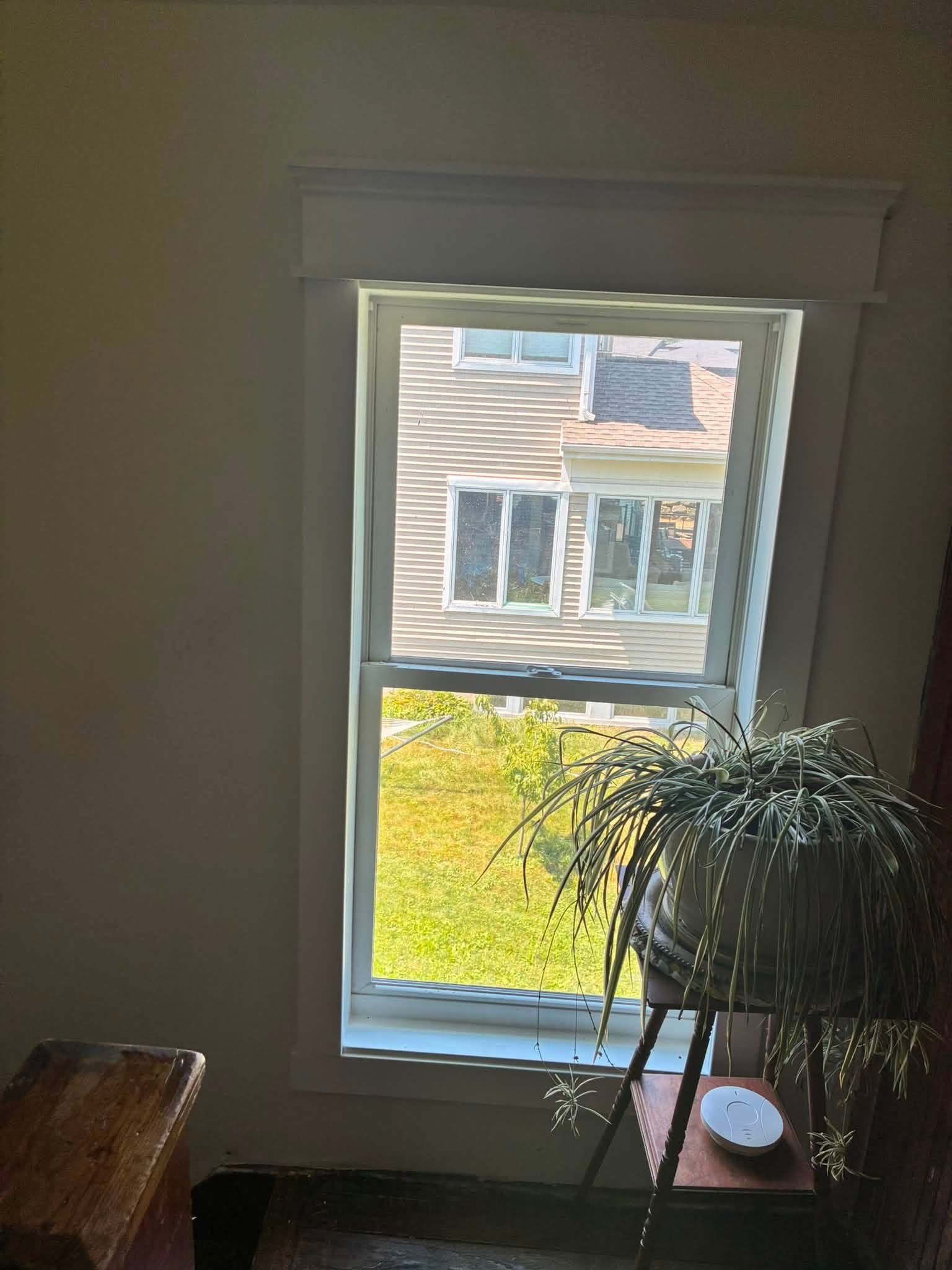 A window in the same house with new trim installed and painted, finished with a built-up header.